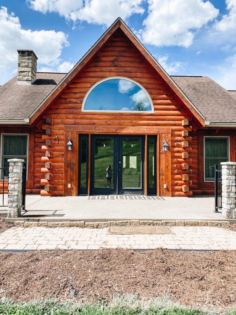 before a front porch refresh | Summer Front Porch by popular Pittsburg life and style blog, Fashionably Late Mom: before image of a log home with double black Fram window doors and a black and white rug. 