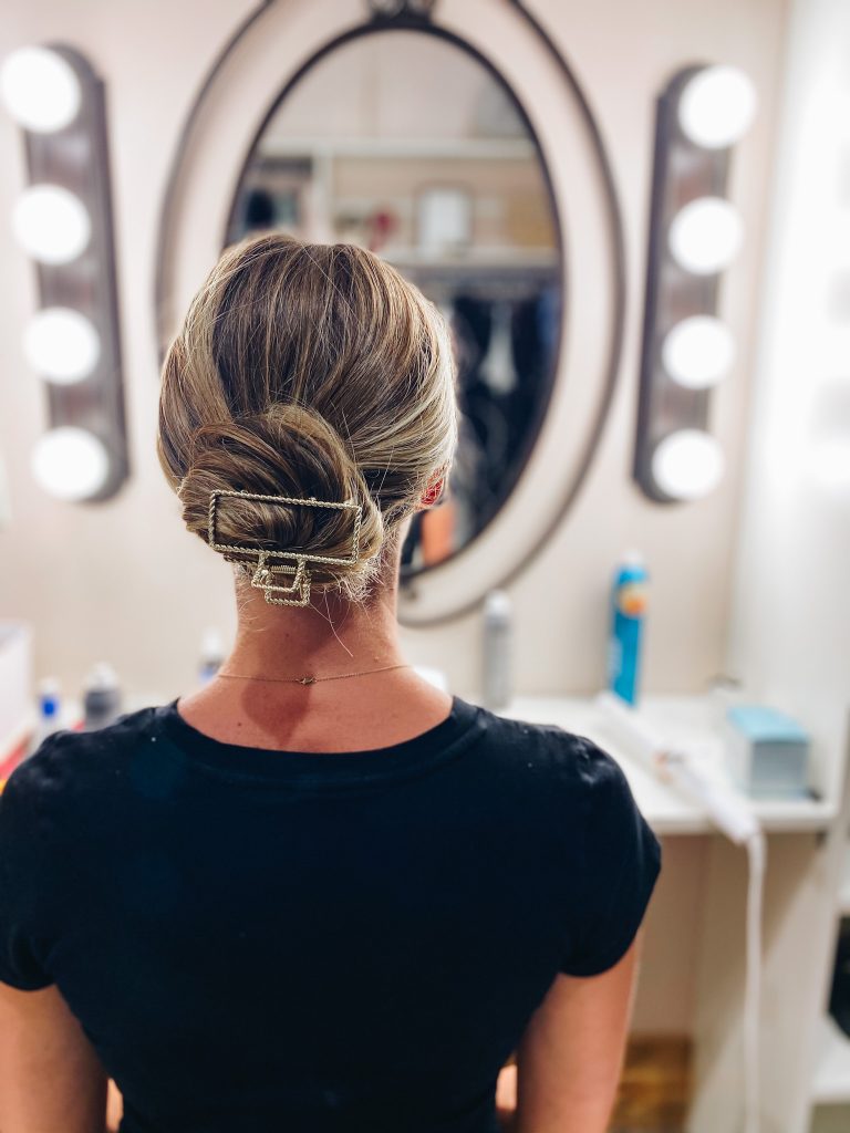 Claw Clip Hairstyles by popular Pittsburgh fashion blog, Fashionably Late Mom: image of a woman putting a claw clip in her hair. 