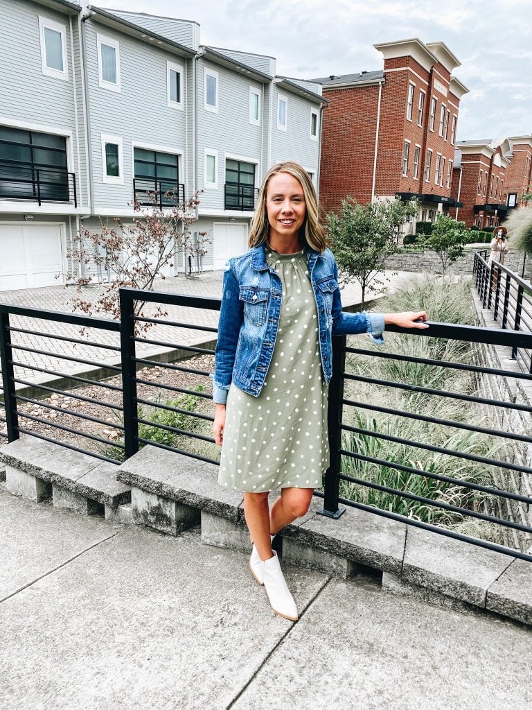 Pink Lily Boutique, polka dot dress, cream booties, denim jacket | Pink Lily by popular Pittsburgh fashion blog, Fashionably Late Mom: image of a woman wearing a Pink Lilly denim jacket, green and white polka dot dress, and white ankle boots. 